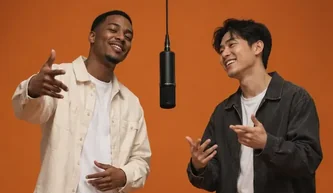 Two friends performing in an orange studio at a hanging microphone